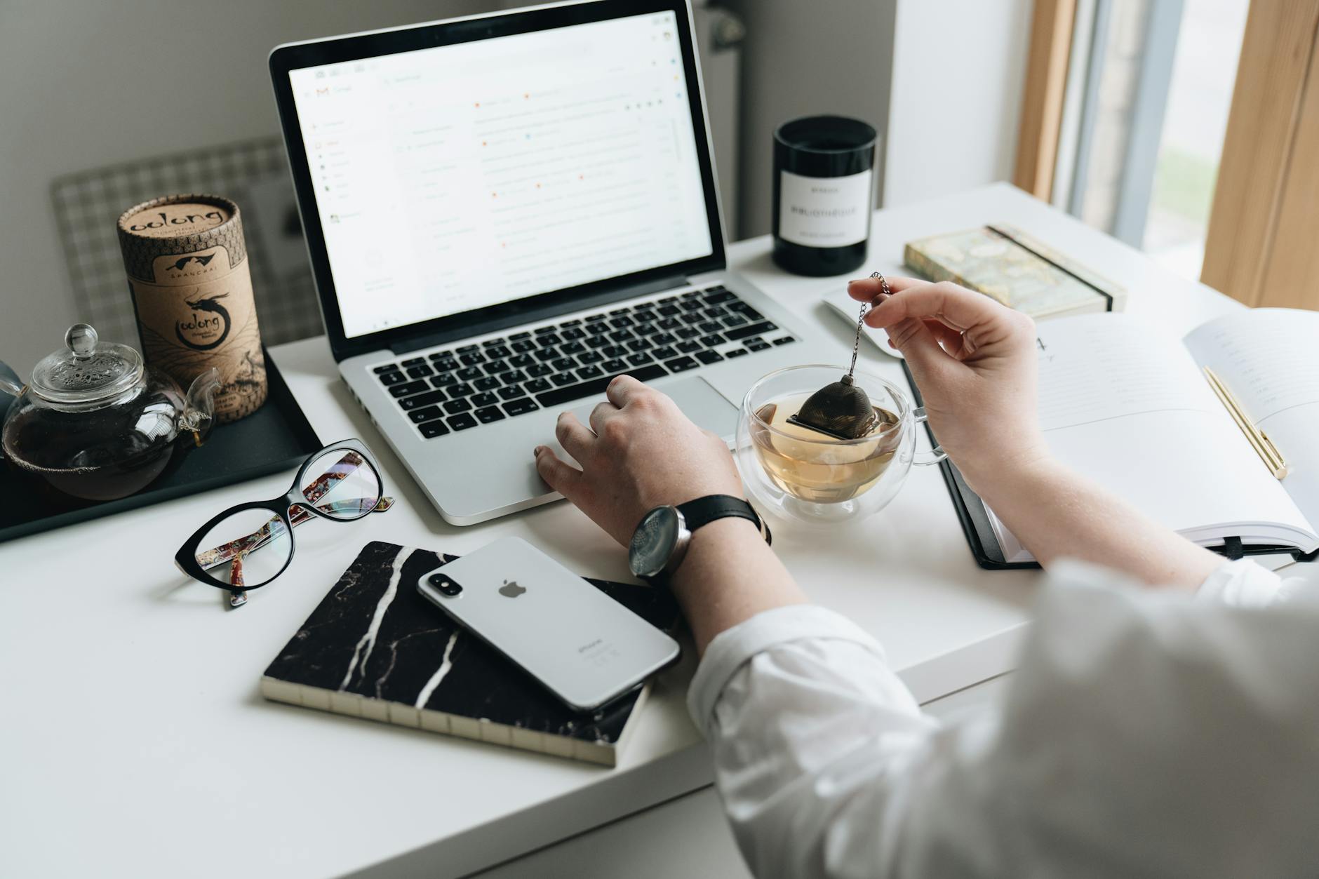 A cozy home office scene with a laptop, tea, and workspace essentials. (Photo by alleksana on Pexels)