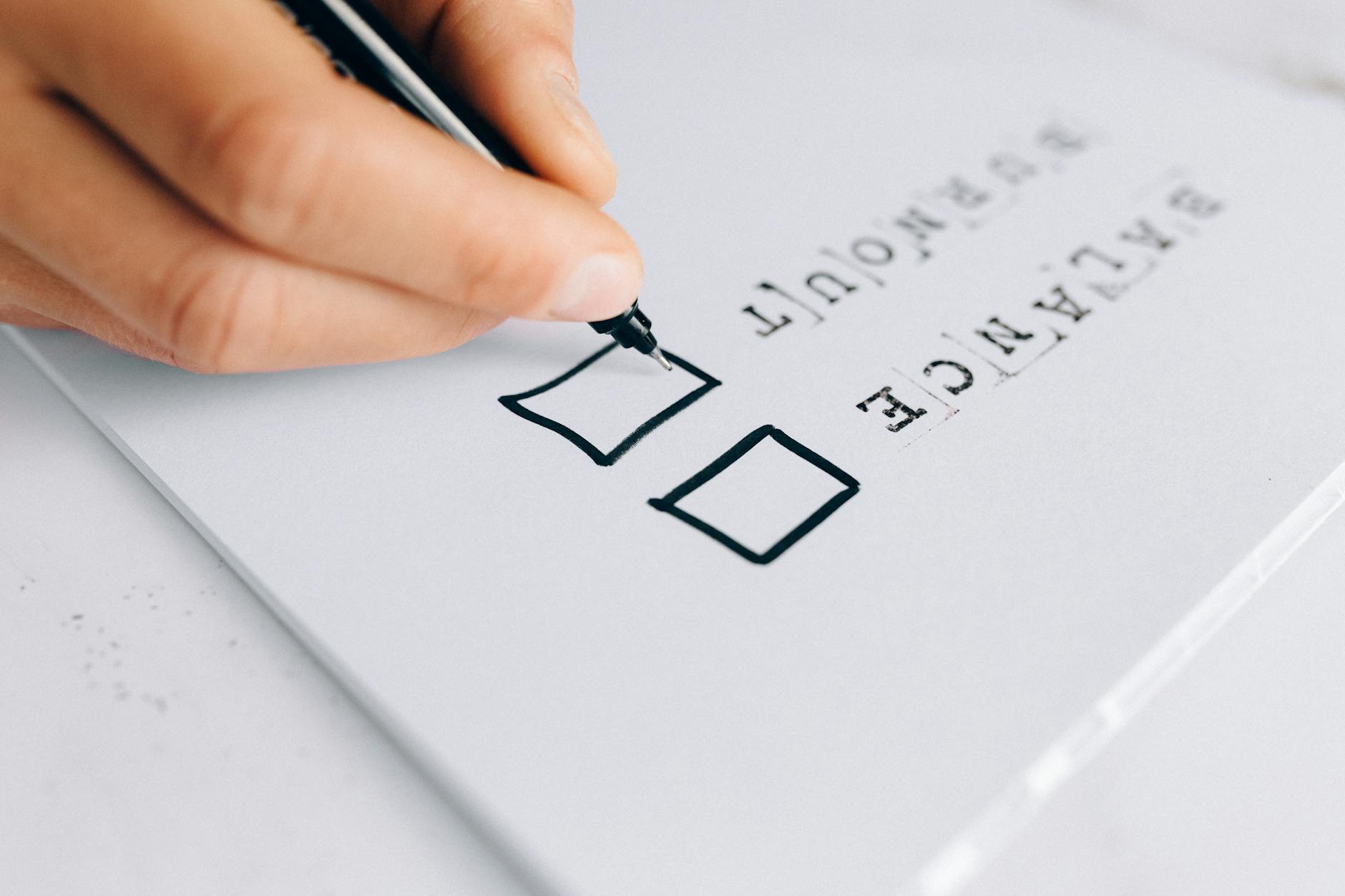 A hand drawing checkboxes on a checklist, themed around balance and burnout. (Photo by Nataliya Vaitkevich on Pexels)