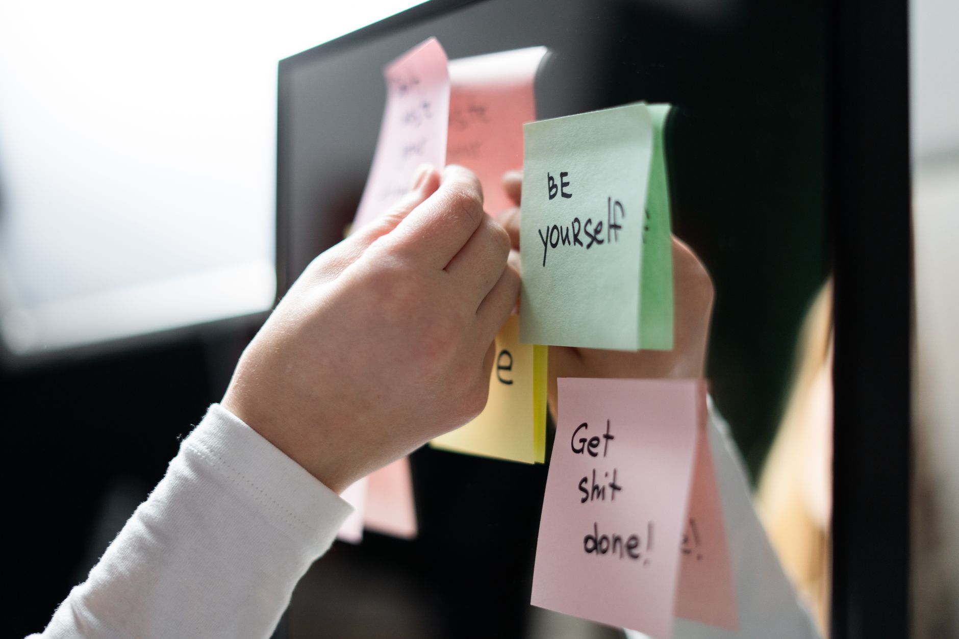 Close-up of hand placing colorful motivational sticky notes on a mirror, inspiring messages. (Photo by cottonbro studio on Pexels)